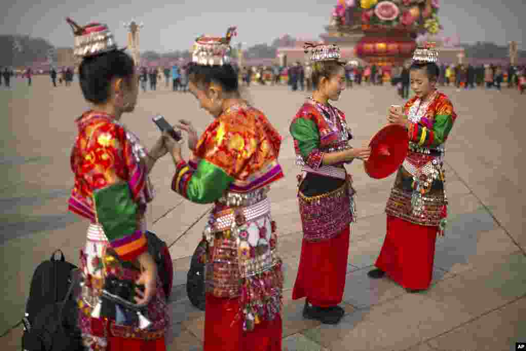 在美國總統唐納德&middot;川普將對中國首都進行為期三天的國事訪問前夕，在北京天安門廣場，穿著少數民族服裝的女子照相，看著智能手機（2017年11月6日）。