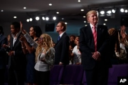 Republican presidential candidate Donald Trump, right, looks on during a church service at Great Faith Ministries in Detroit, Sept. 3, 2016.