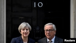 FILE - Britain's Prime Minister Theresa May welcomes Head of the European Commission, President Jean-Claude Juncker to Downing Street in London, April 26, 2017. 