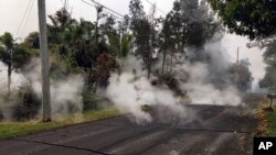 This May 7, 2018, photo from the U.S. Geological Survey shows gas and steam rising from multiple fissures on Moku Street in the Leilani Estates Subdivision near Pahoa on the island of Hawaii.