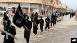 FILE - Fighters from the Islamic State group march in Raqqa, Syria, Jan. 14, 2014.