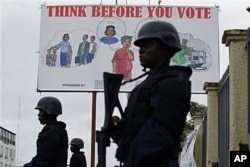 FILE - Liberian police equipped with riot gear stand guard outside the headquarters of the National Elections Commission in Monrovia, Liberia, Oct. 13, 2011.