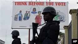 Liberian police equipped with riot gear stand guard outside the headquarters of the National Elections Commission as the NEC prepared to announce the first partial presidential election results, in Monrovia, Liberia, Oct. 13, 2011.