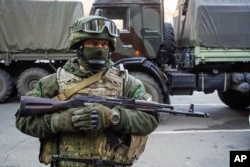 FILE - A pro-Russia rebel stands guard during preparations for a prisoner exchange in Donetsk, eastern Ukraine.