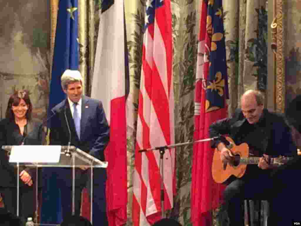 Walikota Paris Anne Hidalgo dan Menteri Luar Negeri AS John Kerry mendengarkan penampilan penyanyi James Taylor di Balai Kota Paris (16/1). (VOA/Pam Dockins)