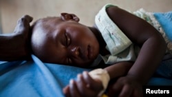 A young girl with malaria rests in a hospital in Sudan.