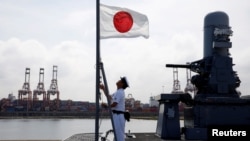 一名水手在日本加賀號直升機航母上升起日本國旗。（2018年9月30日）