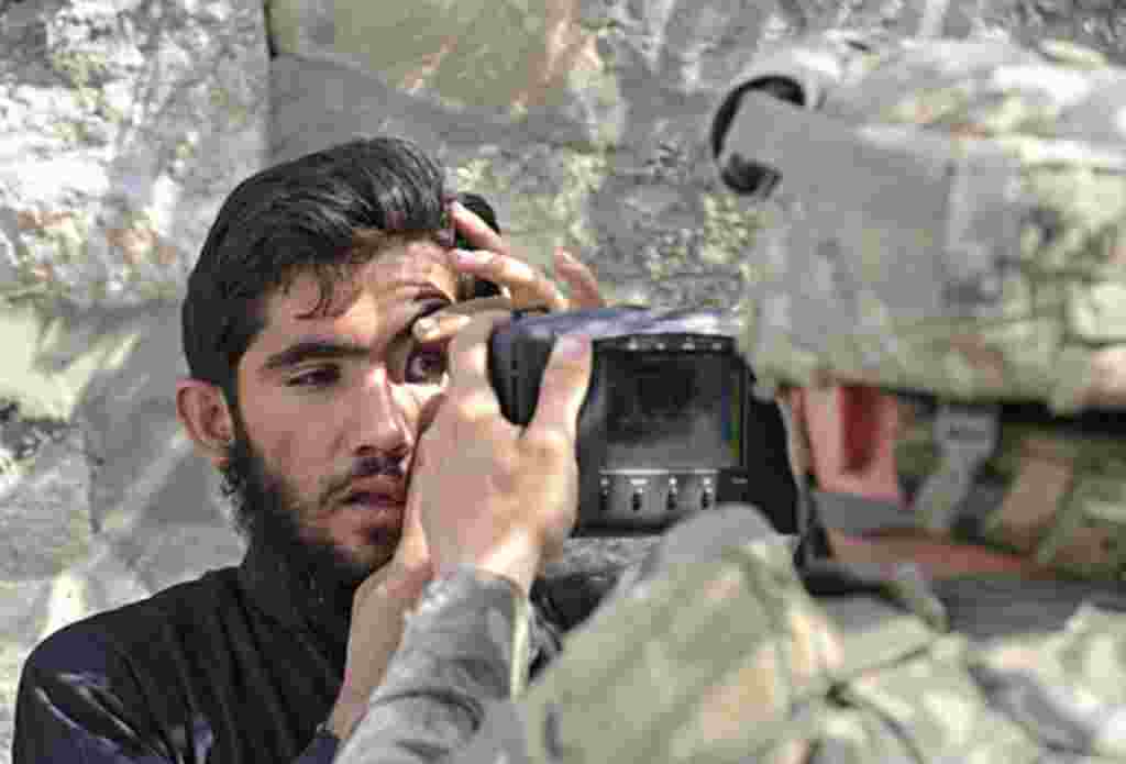 Un soldado estadounidense registra los ojos de un residente afgano con un sistema de identificación biométrico automatizado, ABIS, durante una misión en Turkham.