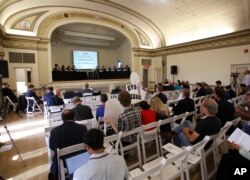 FILE - Speakers comment to the board during the first of three public hearings on the Trump administration's proposal to roll back car-mileage standards in a region with some of the nation's worst air pollution in Fresno, Calif., Sept. 24, 2018.