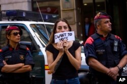 A woman protests holding a sign next to Mossos d'Esquadra police officers, in Barcelona, Spain, Sept. 20, 2017.