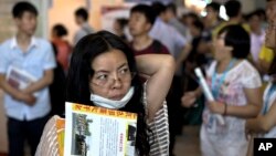 FILE - Chinese woman with her resume hunts for a job during a job fair held at the China International Exhibition Center in Beijing.