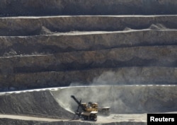 FILE - A mechanical shovel scoops up rocks to be loaded onto waiting dump trucks during a normal work day at the Chuquicamata open pit copper mine in northern Chile, April 1, 2011.