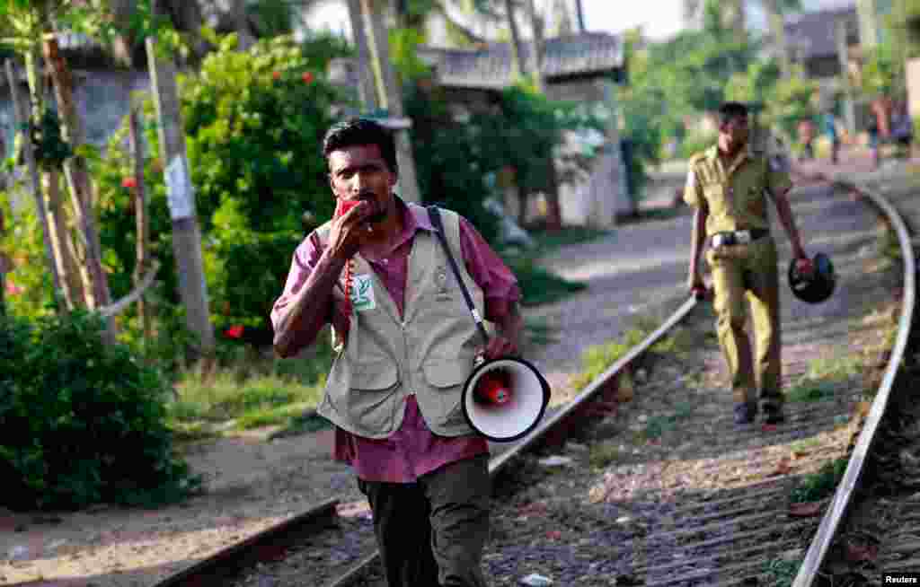 An officer from the disaster management committee announces to people living near the sea to leave their houses after the government announced a Tsunami warning in Colombo, Sri Lanka. (Reuters)