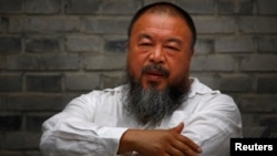 Chinese dissident artist Ai Weiwei sits on a chair in the courtyard of his studio, in Beijing, June 20, 2012.