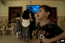 In this Aug. 19, 2018 photo, children watch a cartoon at the state-run al-Zuhour Orphanage, which now hosts children of Islamic State militants, in Baghdad, Iraq.