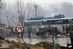 Indian paramilitary soldiers stand by the wreckage of a bus after an explosion in Pampore, Indian-controlled Kashmir, Thursday, Feb. 14, 2019.