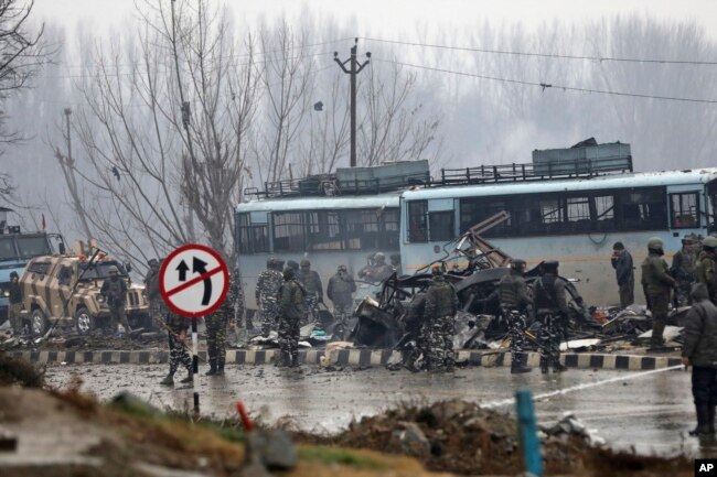 FILE - Indian paramilitary soldiers stand by the wreckage of a bus after an explosion in Pampore, Indian-controlled Kashmir, Feb. 14, 2019.