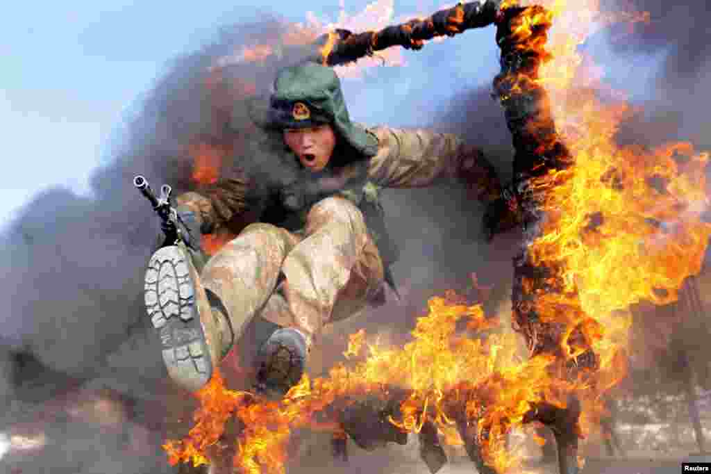 A soldier from the People&#39;s Liberation Army jumps through a ring of fire as part of training in Heihe, China.