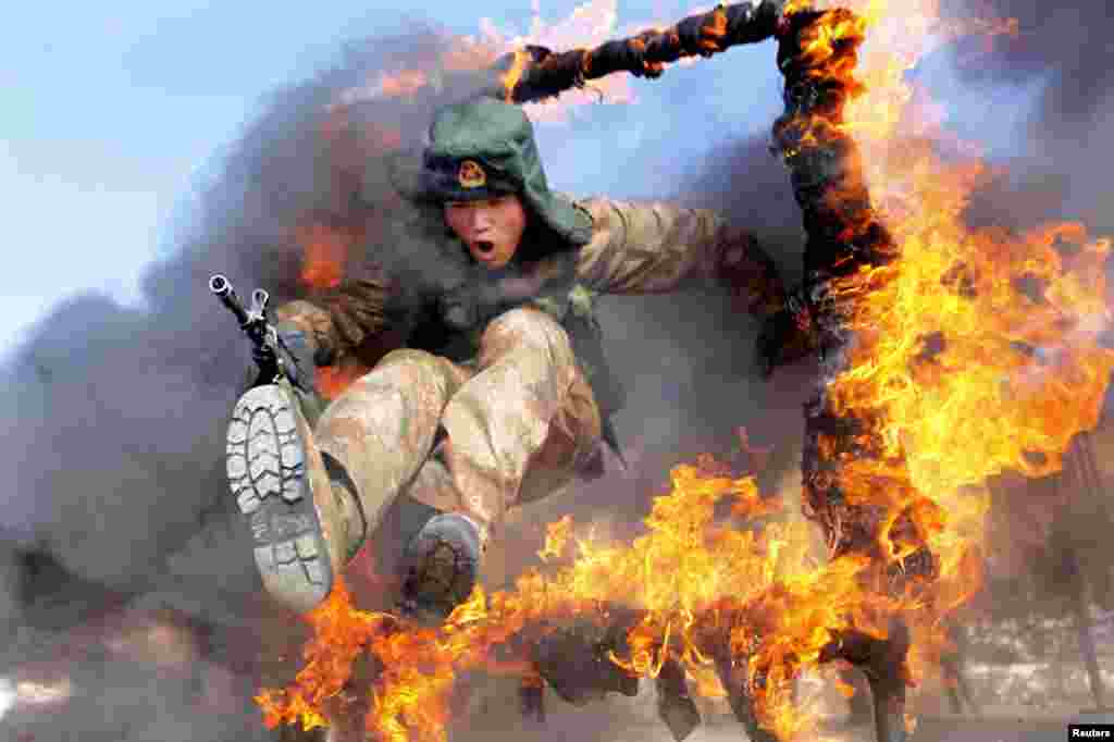 A frontier soldier from the People's Liberation Army jumps through a ring of fire as part of training in Heihe, Heilongjiang province, China.