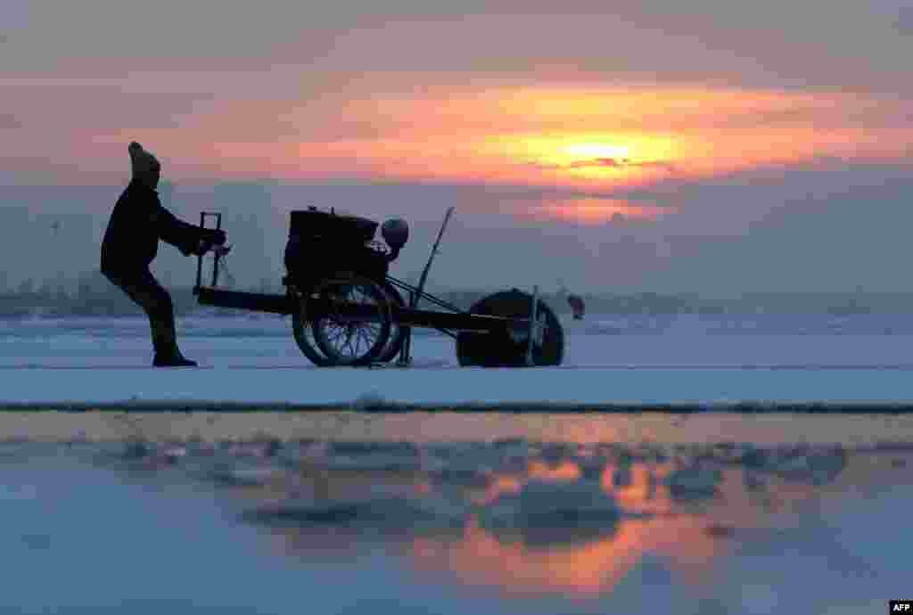 People cut ice blocks used for Harbin international ice and snow festival from the frozen Songhua river in Harbin, northeast China's Heilongjiang province, Dec. 9, 2014. The annual festival is set to kick off on January 5, 2015 and last for a month, local media reported.