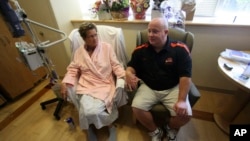 FILE - Laurie Cavanaugh holds hands with her husband Mike Cavanaugh in her hospital room after surgery at Oregon Health & Science University Hospital, in Portland, Oregon.