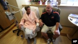 FILE - Laurie Cavanaugh holds hands with her husband Mike Cavanaugh in her hospital room after surgery at Oregon Health & Science University Hospital, in Portland, Oregon.