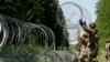 FILE - Lithuanian army soldiers install razor wire on the border with Belarus in Druskininkai, Lithuania, July 9, 2021. 