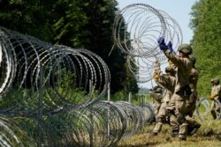 FILE - Lithuanian army soldiers install razor wire on the border with Belarus in Druskininkai, Lithuania, July 9, 2021.