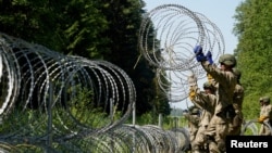 FILE - Lithuanian army soldiers install razor wire on the border with Belarus in Druskininkai, Lithuania, July 9, 2021. 