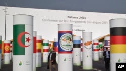 Delegates walk outside the main entrance of the United Nations Climate Change Conference in Le Bourget, outside Paris, Nov. 27, 2015. 