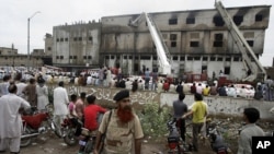 People gather at the site of burnt garment factory in Karachi, Pakistan, September 12, 2012.