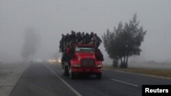 FILE - Migrants ride in the back of a truck during their journey toward the United States, in Los Olivos, Mexico, Feb. 2, 2019. On Thursday dozens of migrants were killed or injured when the truck they were riding in crashed in Mexico.