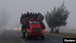 FILE - Migrants ride in the back of a truck during their journey toward the United States, in Los Olivos, Mexico, Feb. 2, 2019. On Thursday dozens of migrants were killed or injured when the truck they were riding in crashed in Mexico.