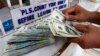 A worker counts U.S. dollar bills and Philippine pesos inside a money changer in Manila, June 19, 2013.