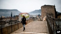 FILE - A woman crosses the old bridge in Mostar, in Bosnia and Herzegovina, Jan. 20, 2013. 