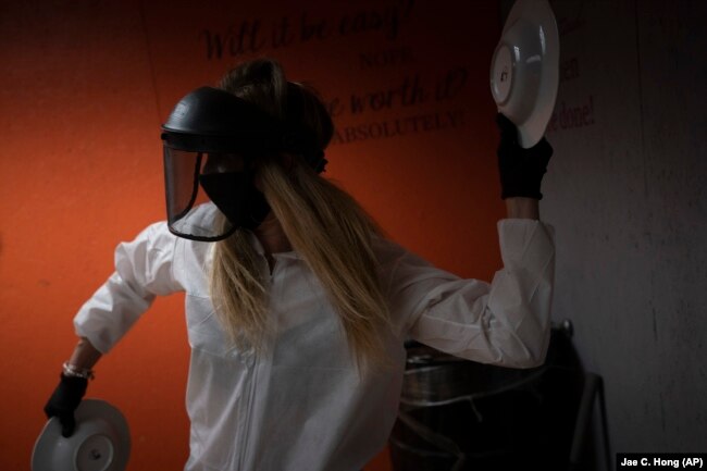 Asia Made, 50, smashes plates against a wall in a rage room during a session to help relieve stress at Smash Rx, Feb. 5, 2021. (AP Photo/Jae C. Hong)
