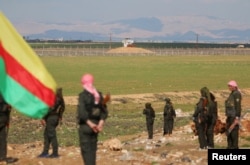 FILE - Kurdish members of the Self-Defense Forces stand near the Syrian-Turkish border in the Syrian city of al-Derbasiyah during a protest against the operations launched in Turkey by government security forces against the Kurds, Feb. 9, 2016.