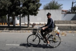 Seorang pria mengendarai sepedanya dengan membawa botol-botol plastik kosong di jalanan kota Kabul, 15 September 2021. (Karim SAHIB / AFP)
