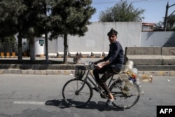 Seorang pria mengendarai sepedanya dengan membawa botol-botol plastik kosong di jalanan kota Kabul, 15 September 2021. (Karim SAHIB / AFP)