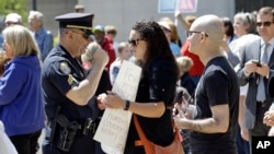 A police officer confronts a woman holding a sign at the North Carolina State Capitol in Raleigh, North Carolina, April 11, 2016.
