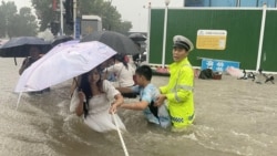 河南省郑州市一名交通警察用一条绳子帮助居民过洪水湍急的街道。 （2021年7月20日）