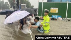 河南省郑州市一名交通警察用一条绳子帮助居民过洪水湍急的街道。 （2021年7月20日）