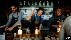 FILE - Starbucks employees prepare coffee in the lobby of the company's annual shareholders meeting in Seattle, Washington, March 23, 2016.