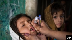 Nhân viên y tế Pakistan cho trẻ em uống vắc xin ngừa sốt bại liệt.