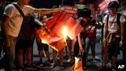 Students burn a Chinese flag as they protest against the visit of Chinese President Xi Jinping during a demonstration outside the Presidential Palace in Manila, Philippines, Nov. 20, 2018.