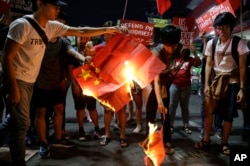 Students burn a Chinese flag as they protest against the visit of Chinese President Xi Jinping during a demonstration outside the Presidential Palace in Manila, Philippines, Nov. 20, 2018.