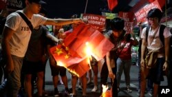 Students burn a Chinese flag as they protest against the visit of Chinese President Xi Jinping during a demonstration outside the Presidential Palace in Manila, Philippines, Nov. 20, 2018.