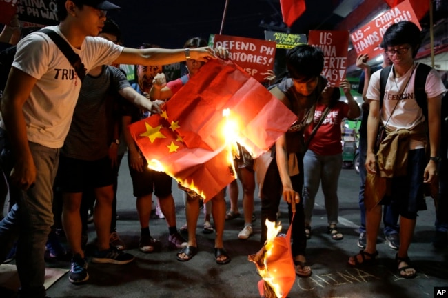 Students burn a Chinese flag as they protest against the visit of Chinese President Xi Jinping during a demonstration outside the Presidential Palace in Manila, Philippines, Nov. 20, 2018.