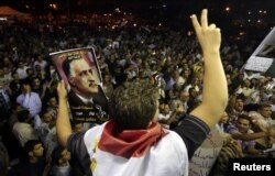 FILE - A protester holds up a poster with an image of former Egypt president Gamal Abdel Nasser during the anniversary of the 1952 Egyptian revolution at Tahrir Square in Cairo, July 23, 2012.