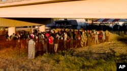 Migrantes, muchos procedentes de Haití, hacen fila el viernes 24 de septiembre de 2021 para subir a autobuses debajo del Puente Internacional de Del Rio, en Del Rio, Texas. 